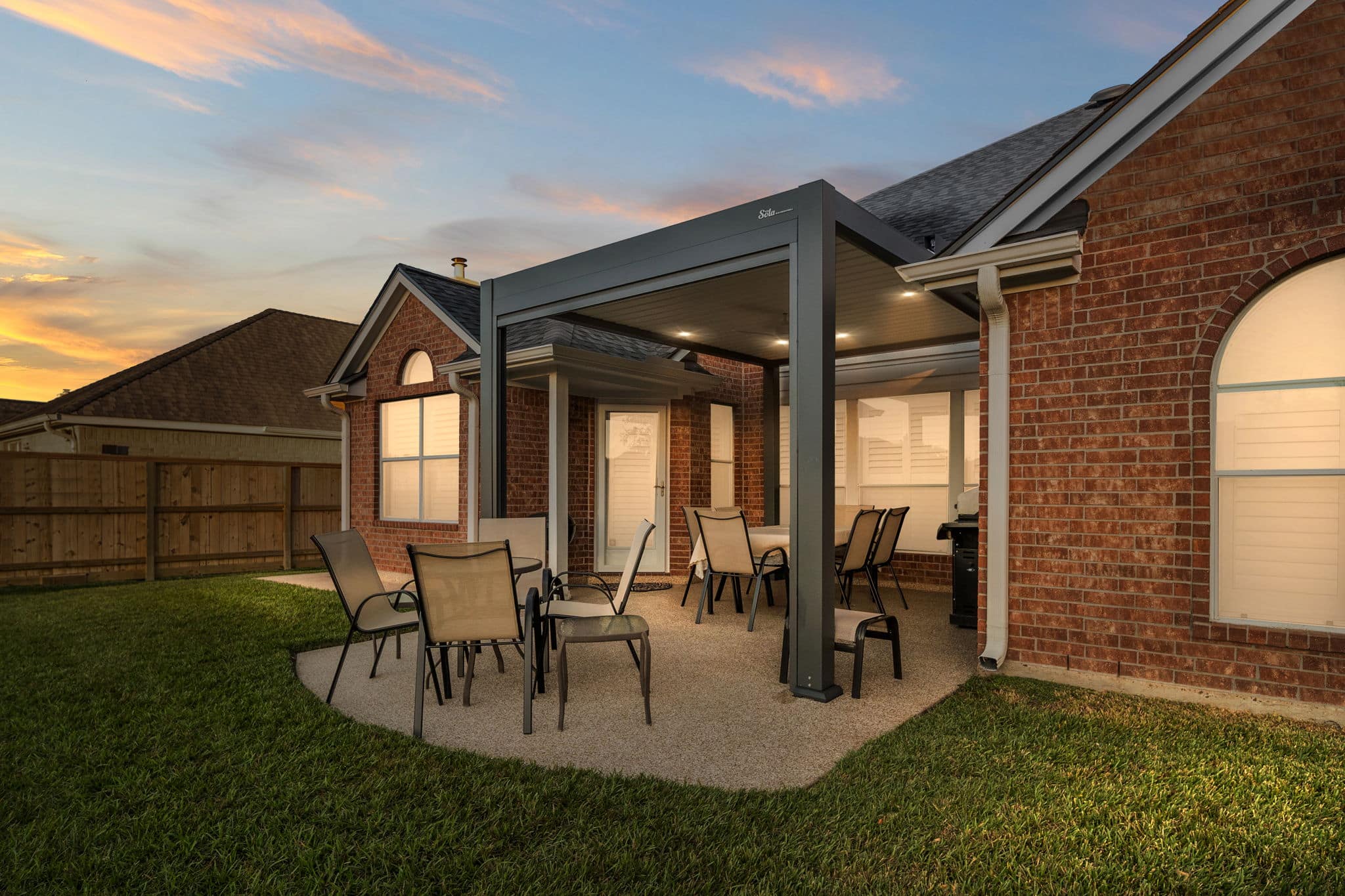 Gray solar pergola in a backyard patio at dusk