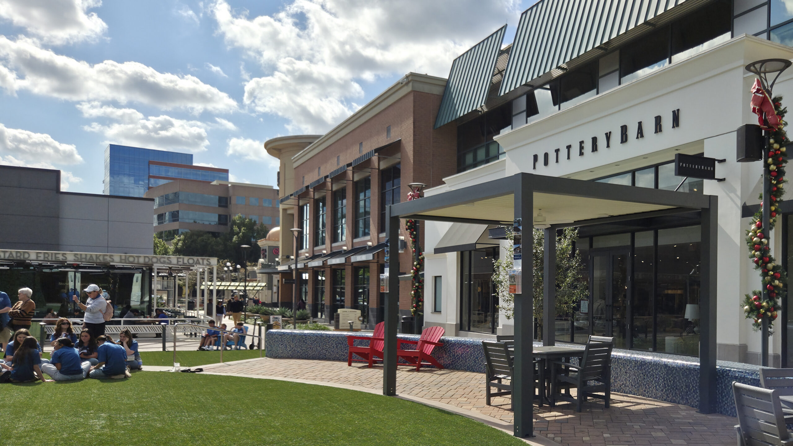 Aluminum solar pergola on shopping mall outdoor patio with seating and holiday decor.