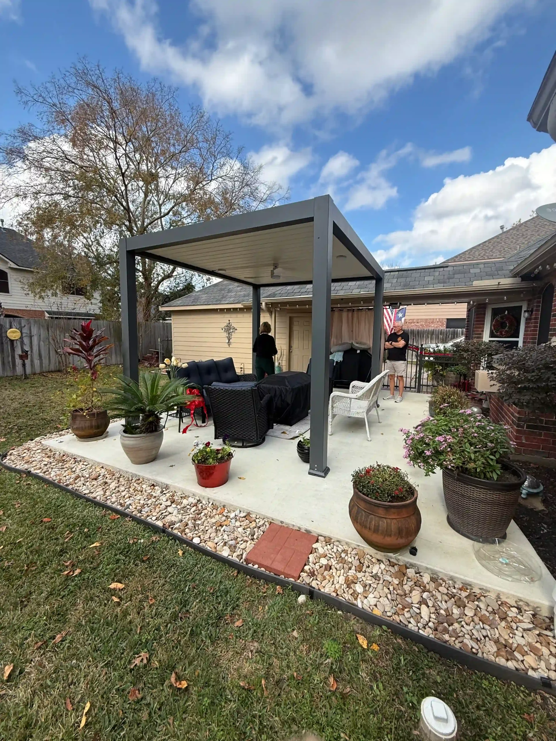 gray frame freestanding louvered pergola with outdoor lounge seating in Houston residential backyard