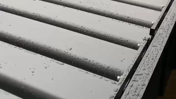 Close-up of sealed motorized louvered pergola roof covered with raindrops during rain